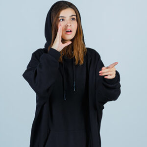 young lady in oversized hoodie, pants pointing aside